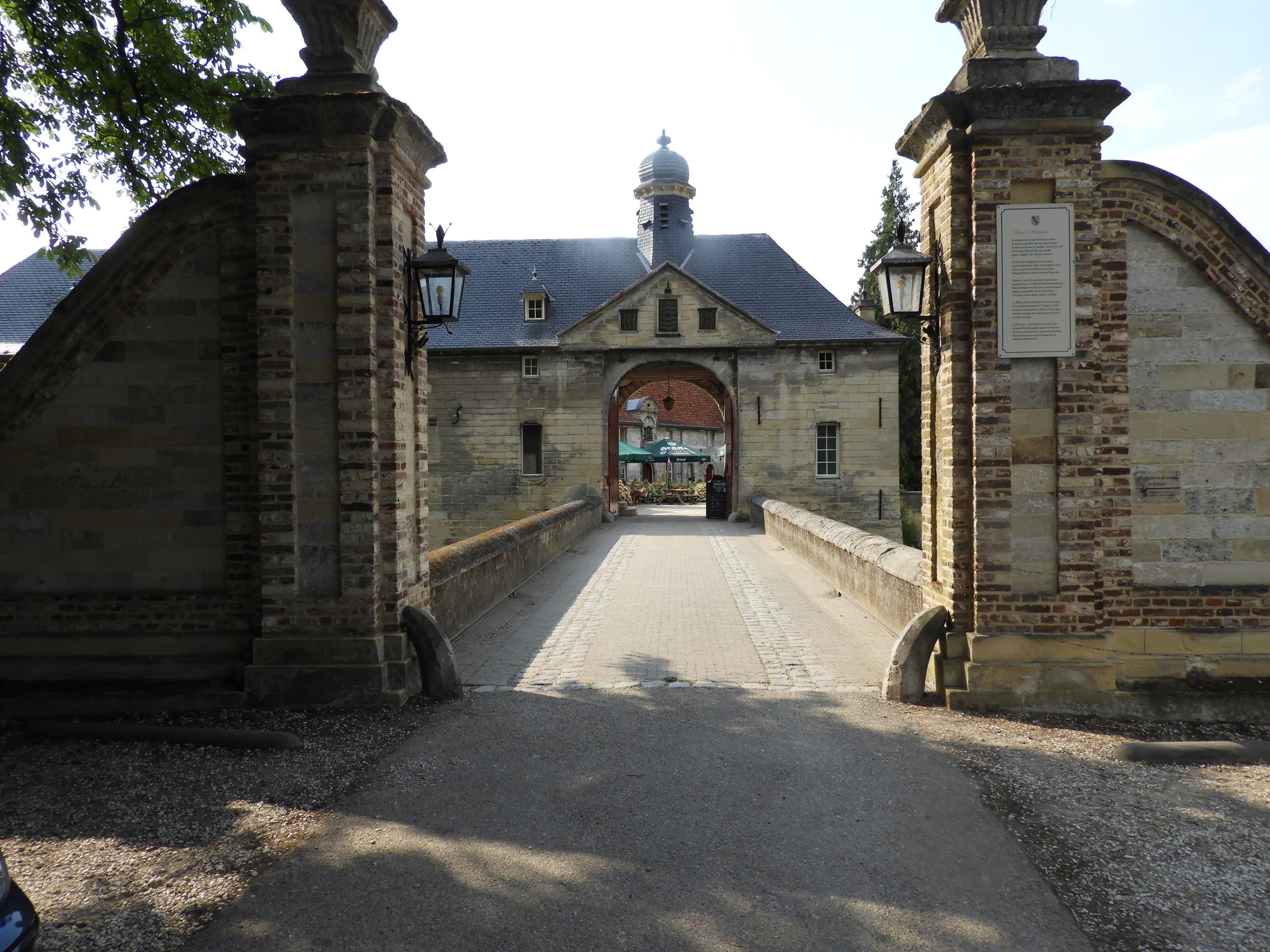A historic building with a central archway, stone walls, and a paved entrance.