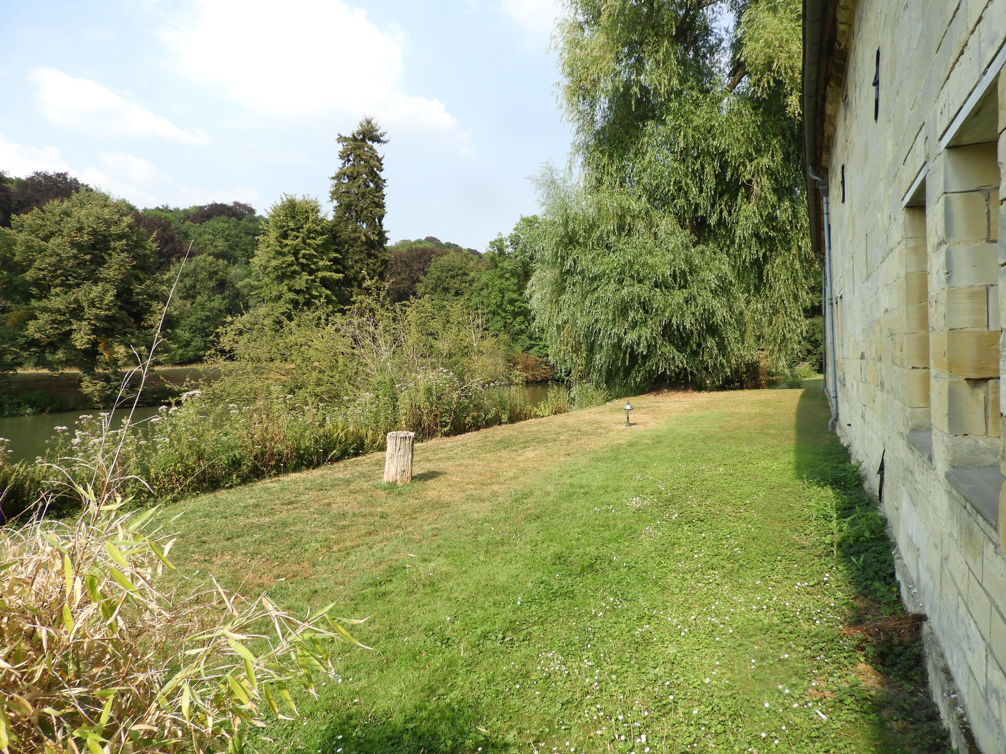 A grassy area with a stone wall and trees.