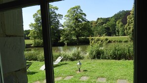 A view of a grassy area with a pond, trees, and a bench. - Kasteel Schaloen (Schin op Geul)