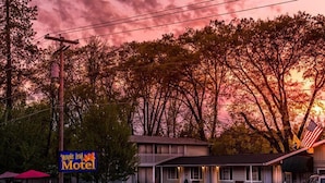 Ein Motel mit Schild, einem eingezäunten Parkplatz und einem Gebäude mit Veranda.