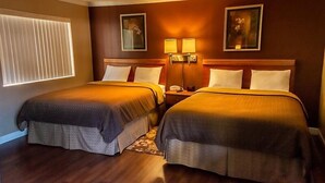 Ein Hotelzimmer mit zwei Betten, einem Nachttisch, Wandlampen und gerahmten Kunstwerken.
