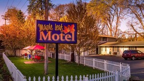 Schild des Maple Leaf Motel mit weißem Zaun und einem roten Auto davor.
