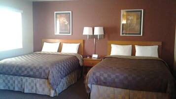 A hotel room with two beds, a nightstand, wall-mounted lamps, and framed artwork.