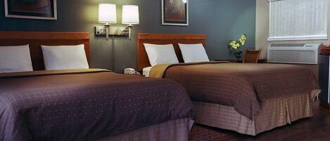 Een hotelkamer met twee bedden, een plafondventilator, wandlampen en een airconditioning.