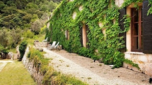 A stone building with ivy-covered walls and a gravel path leading to a seating area. - Hotel Mirabó De Valldemossa (Valldemossa)
