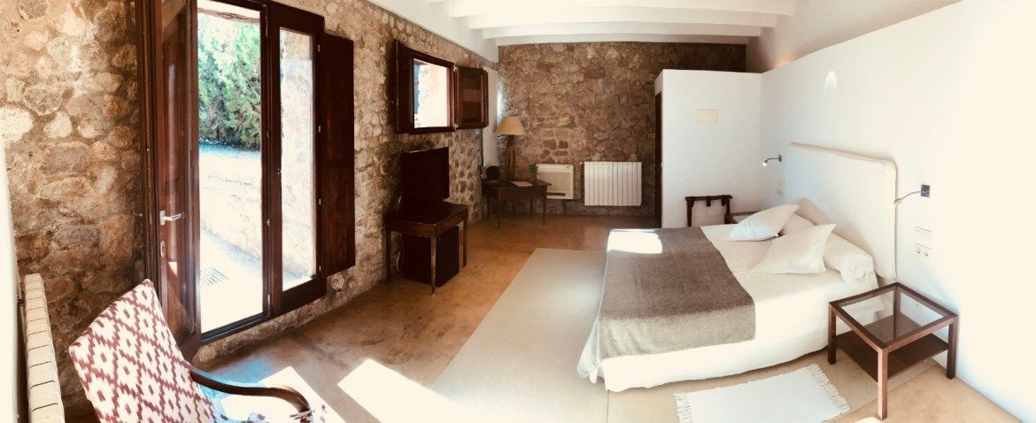 Un dormitorio con pared de piedra, cama, escritorio y silla.