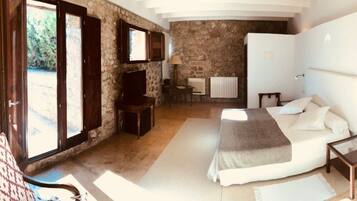 Un dormitorio con pared de piedra, cama, escritorio y silla.