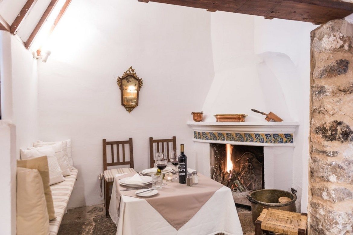 A cozy dining area with a fireplace, wooden furniture, and a table set for two.