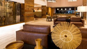 A modern lobby with leather sofas, a bar area, and decorative vases. - Ritz Hotel Leblon (Rio de Janeiro)