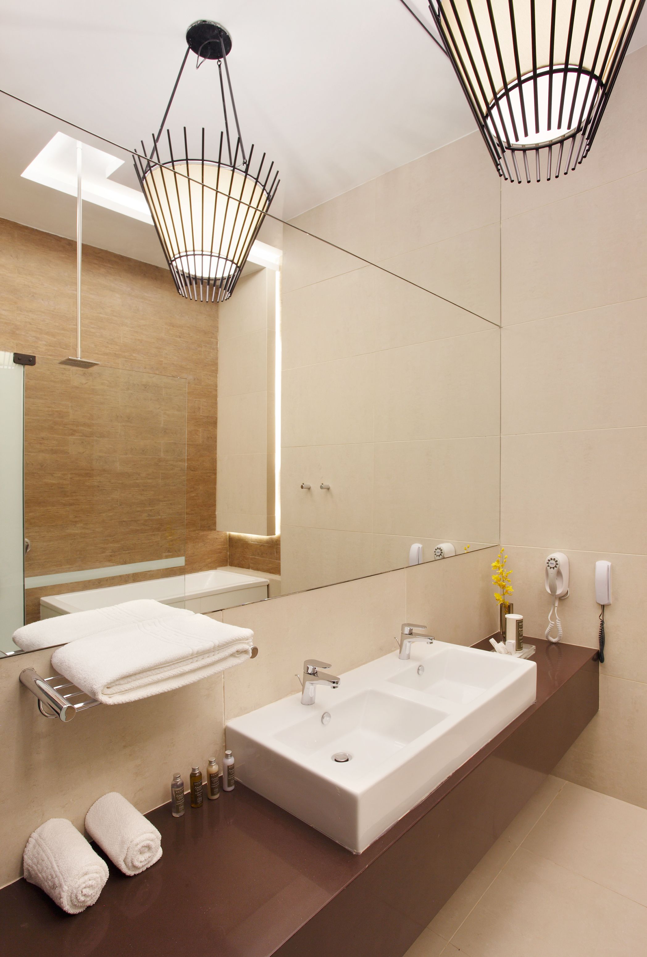 Un baño moderno con un espejo grande, dos lavamanos, una ducha y un perchero para toallas.