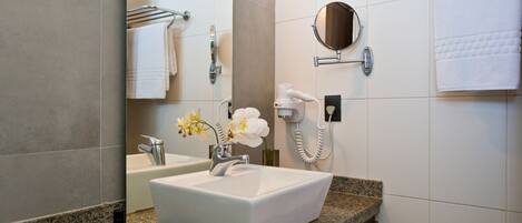 A modern bathroom with a white sink, granite countertop, and a large mirror.