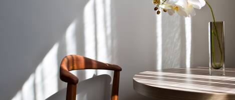 A wooden chair and a table with a vase of flowers.