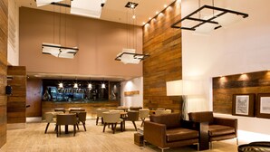 A spacious lobby with a bar area, leather seating, and a modern chandelier. - Ritz Hotel Leblon (Rio de Janeiro)