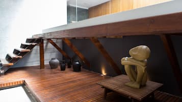 Una escala de fusta amb disseny modern, una banca de fusta i una escultura en un espai interior contemporani.