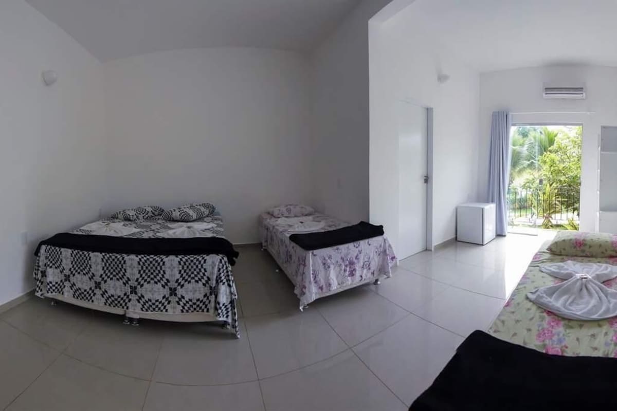 Una habitación con dos camas, una mesita y vistas al exterior con zonas verdes.