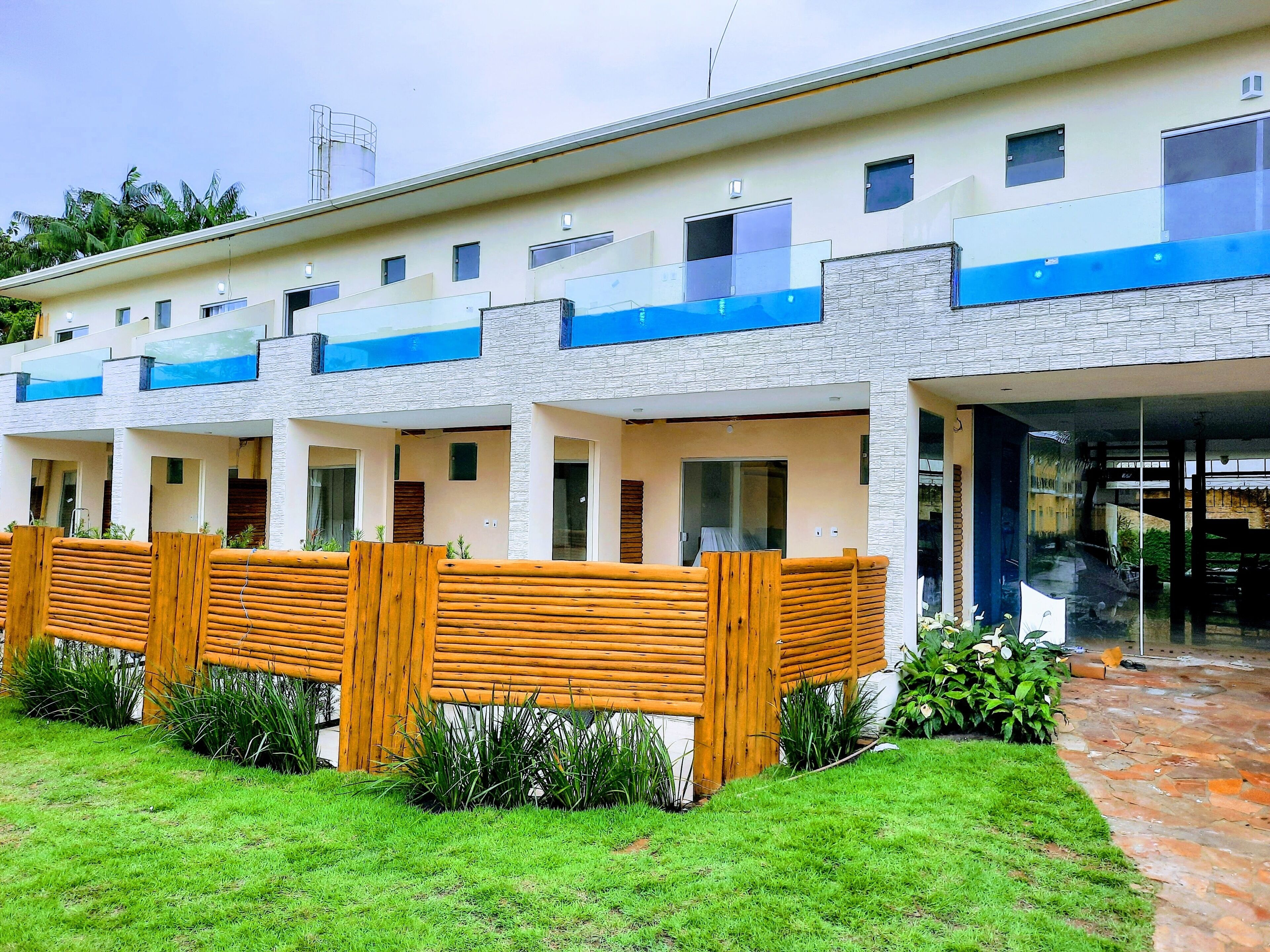 A modern hotel with multiple units, each featuring a balcony and a stone facade.