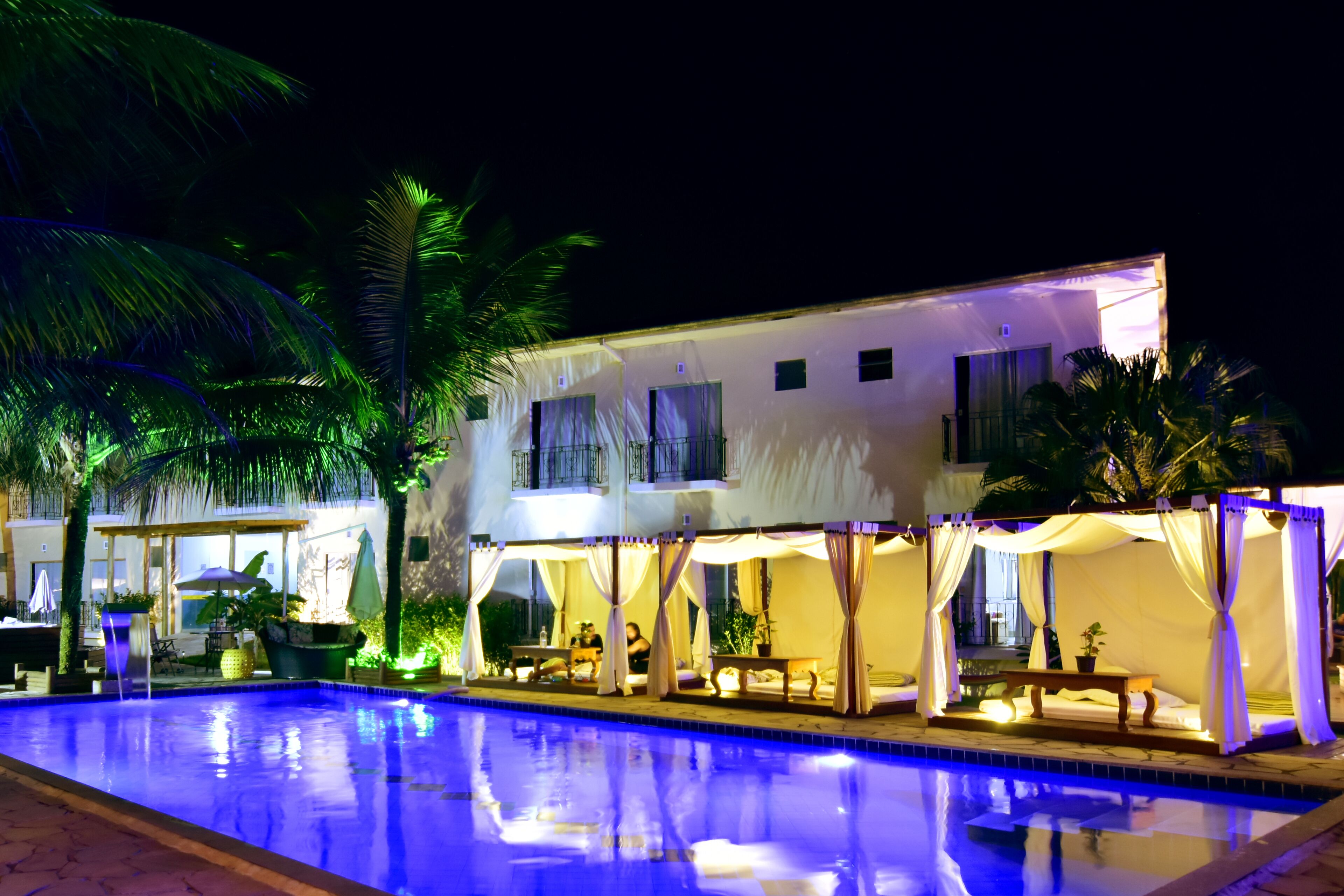 A poolside area with a pool, a covered seating area, and a building with multiple windows.