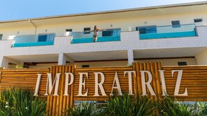 Une enseigne d’hôtel portant le nom « IMPERATRIZ » et un balcon où se trouve une personne.