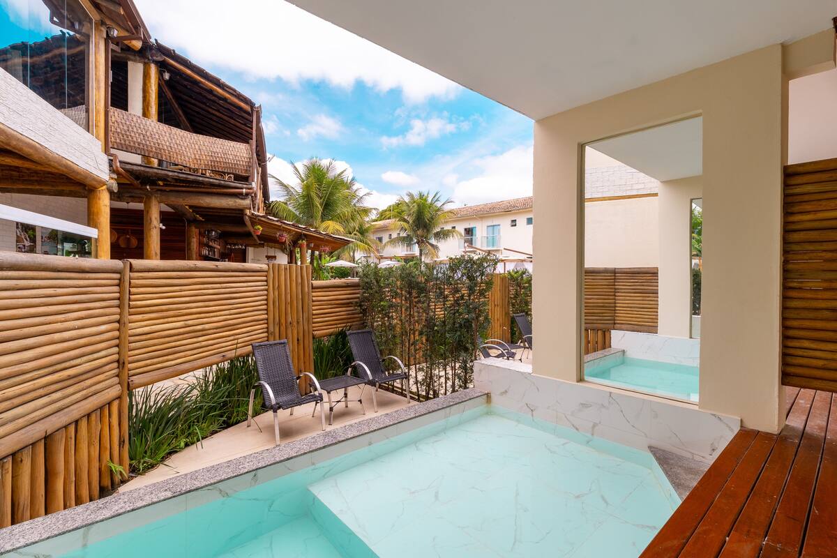 A pool area with lounge chairs, a wooden deck, and a view of the surrounding buildings.