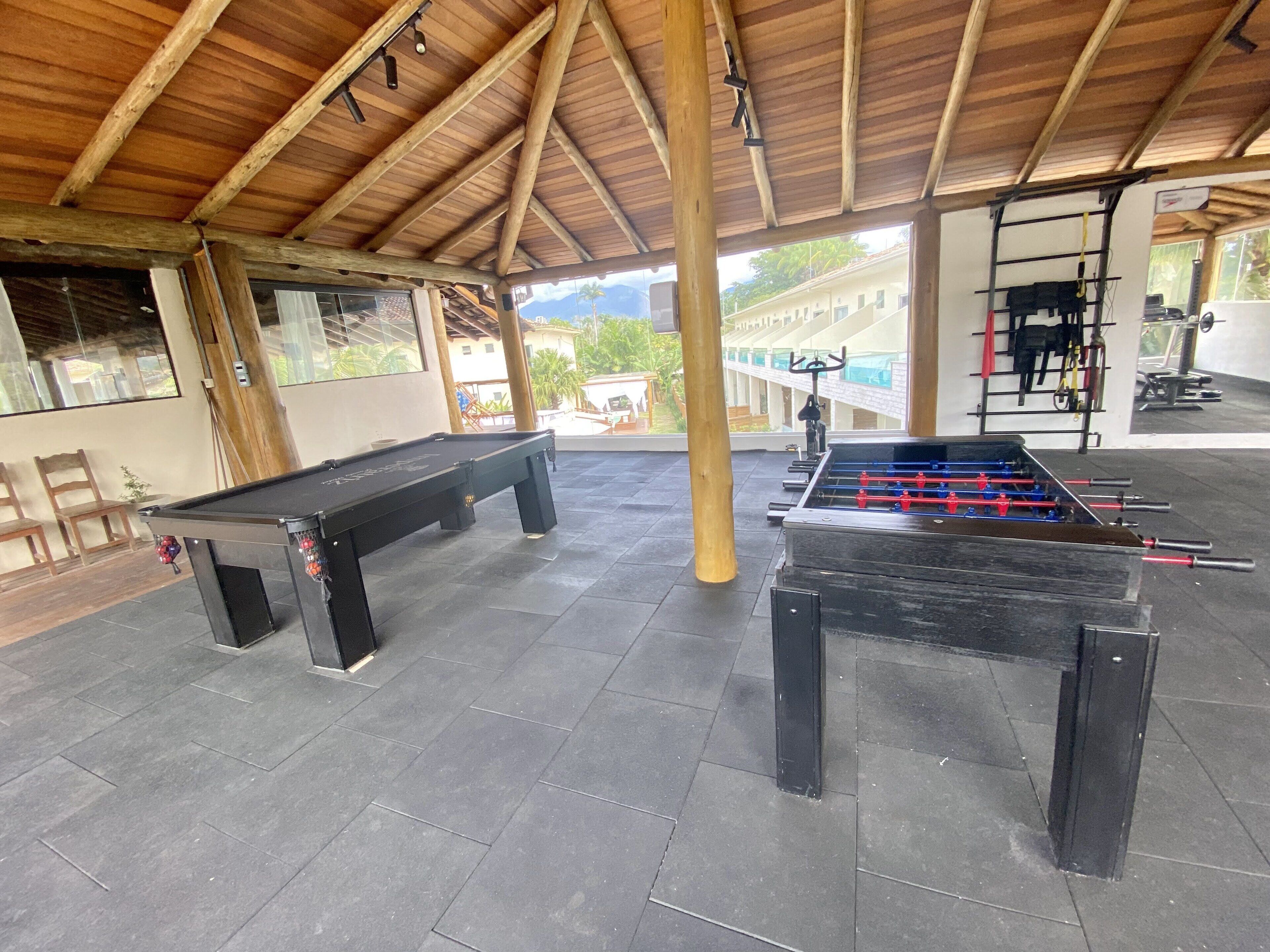Un área recreativa interior con mesa de billar, mesa de futbolín y equipo de ejercicio.