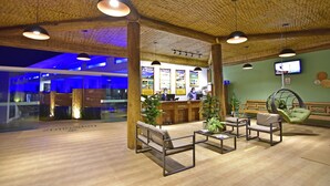 Un hall d’entrée avec un plancher en bois, un comptoir de réception et des espaces de détente comprenant un canapé et des fauteuils.
