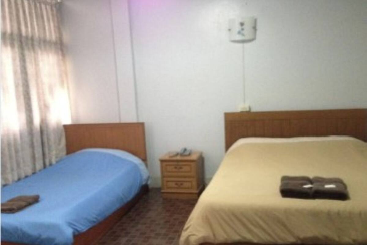 A bedroom with two beds, a nightstand, and a wall socket.