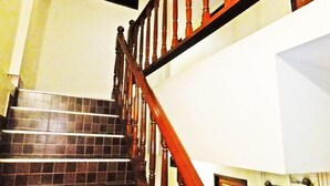 A staircase with wooden balusters and dark tiled steps. - White Orchid Inn (Bangkok)