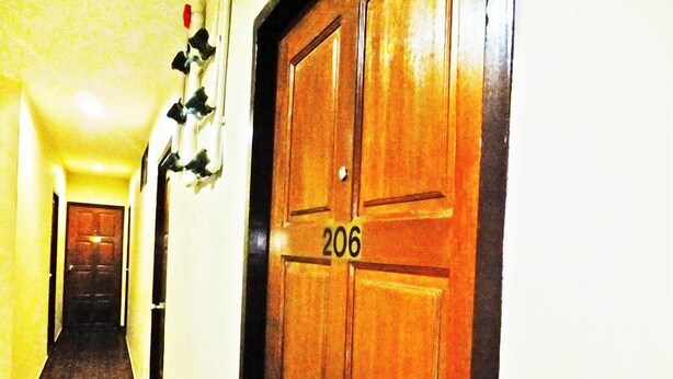A hallway with a wooden door labeled 206, leading to a room. - White Orchid Inn (Bangkok)