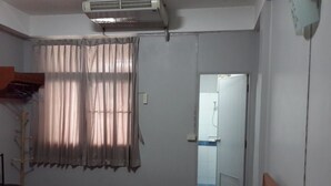 A bedroom with a bed, a window with curtains, a door leading to a bathroom, and an air conditioning unit on the ceiling. - White Orchid Inn (Bangkok)