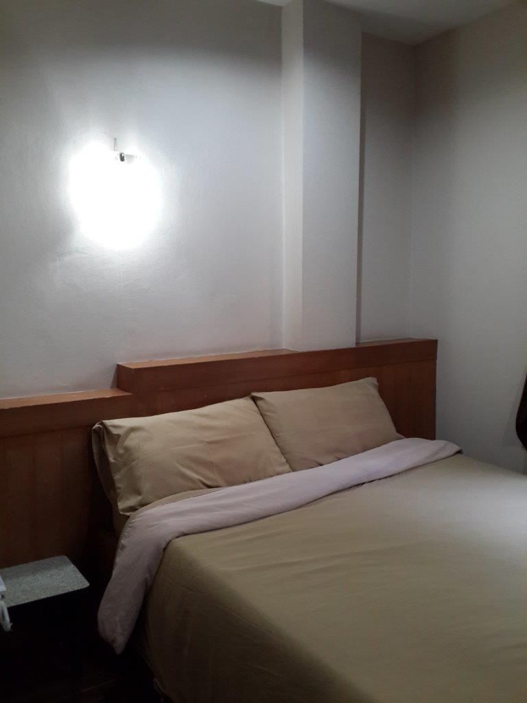 A single bed with a wooden headboard and a beige bedspread.
