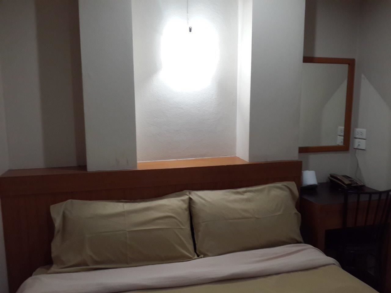 A hotel room with a bed, a desk, and a mirror.