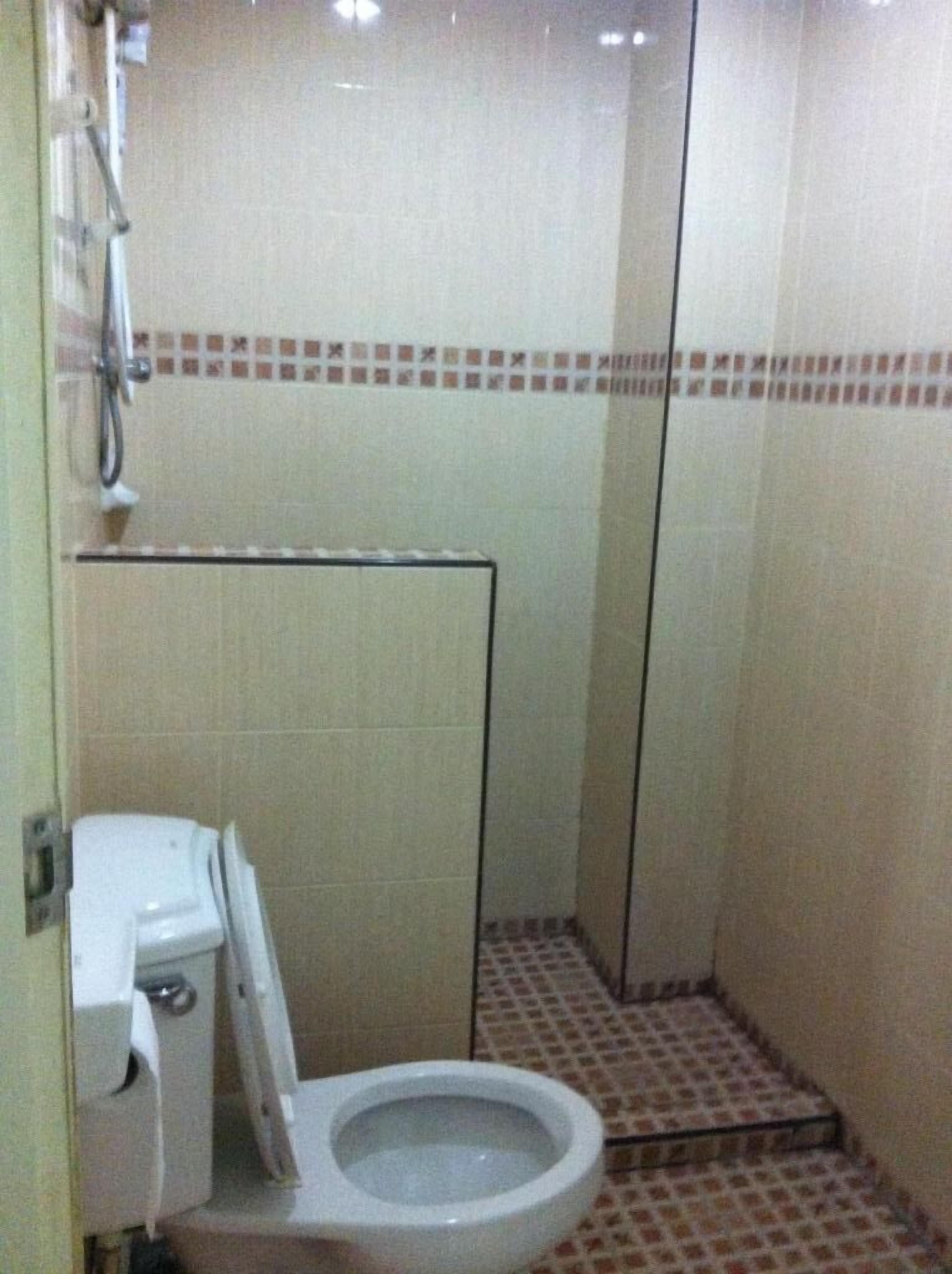 A small, tiled bathroom with a toilet, a shower, and a tiled floor.