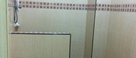 Un baño pequeño con azulejos, un inodoro, una ducha y piso de azulejos.