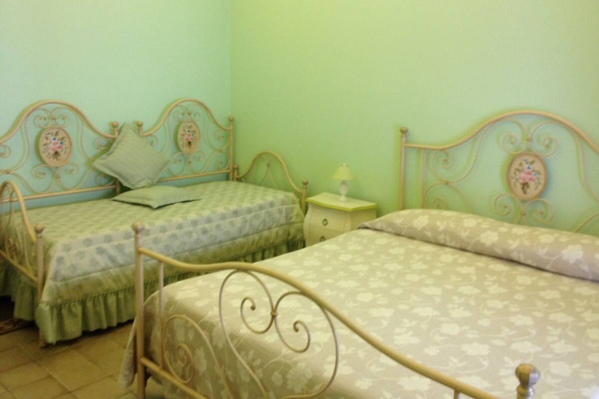 Ein Schlafzimmer mit zwei Betten, jeweils mit einem blumengemusterten Kopfteil und einem Nachttisch mit Lampe.