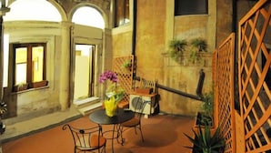 Un patio con una mesa redonda y sillas, una planta en maceta y una valla de madera.