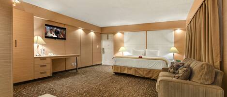 Une chambre d’hôtel comprenant un lit, un canapé, un bureau, une télévision et une salle de bain.