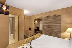 A hotel room with a bed, a desk, and a shower area. - Ocean Beach Palace Hotel and Suites (Fort Lauderdale)