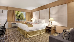 Ein Hotelzimmer mit einem großen Bett, Nachttischen, einem Schreibtisch und einem Sessel.