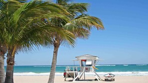 A lifeguard tower on a beach with palm trees and the ocean in the background. - Ocean Beach Palace Hotel and Suites (Fort Lauderdale)