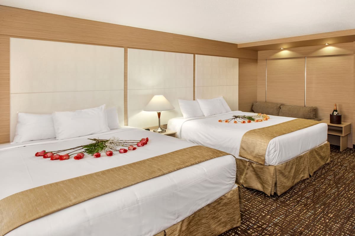 Ein Hotelzimmer mit zwei Betten, einem Nachttisch, einer Lampe und einer Champagnerflasche.