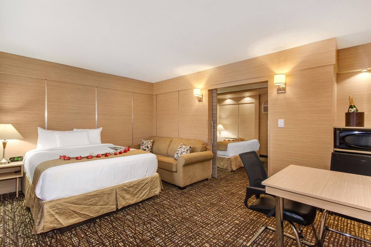 Ein Hotelzimmer mit einem großen Bett, einer Sitzecke, einem Schreibtisch und einer Mikrowelle.