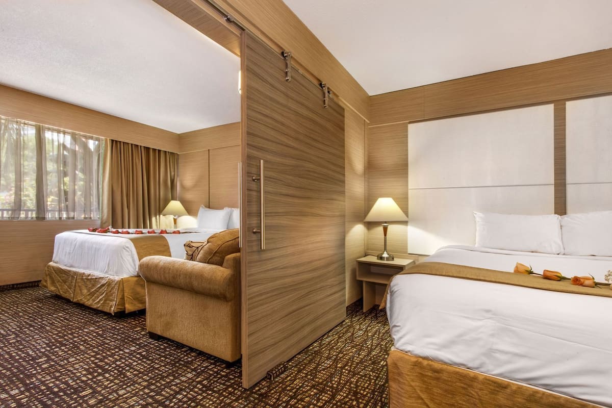 Ein Hotelzimmer mit zwei Betten, einer Couch, einer Holzwand und einem gemusterten Teppich.