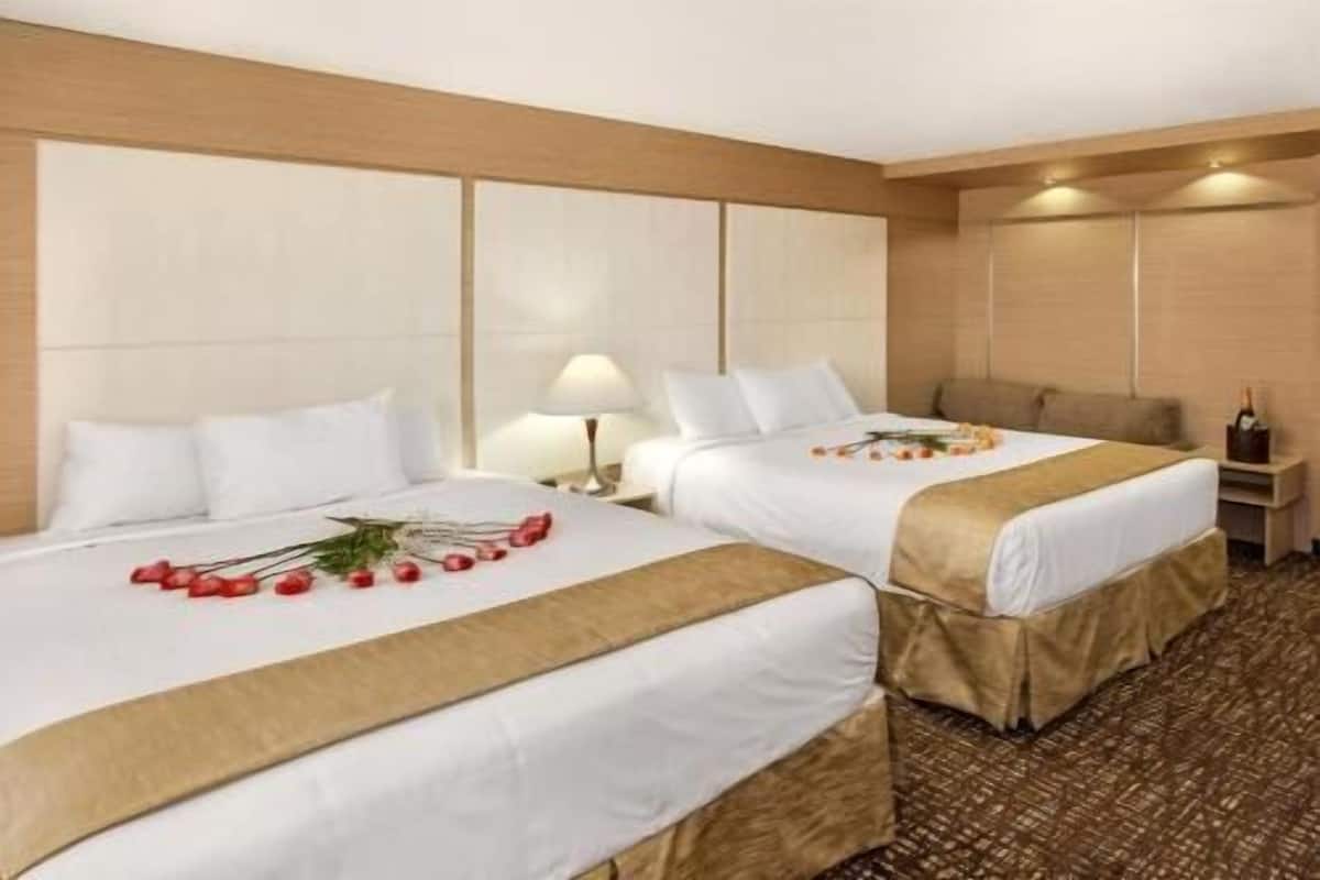 Ein Hotelzimmer mit zwei Betten, einem Nachttisch mit Lampe und einer Champagnerflasche.