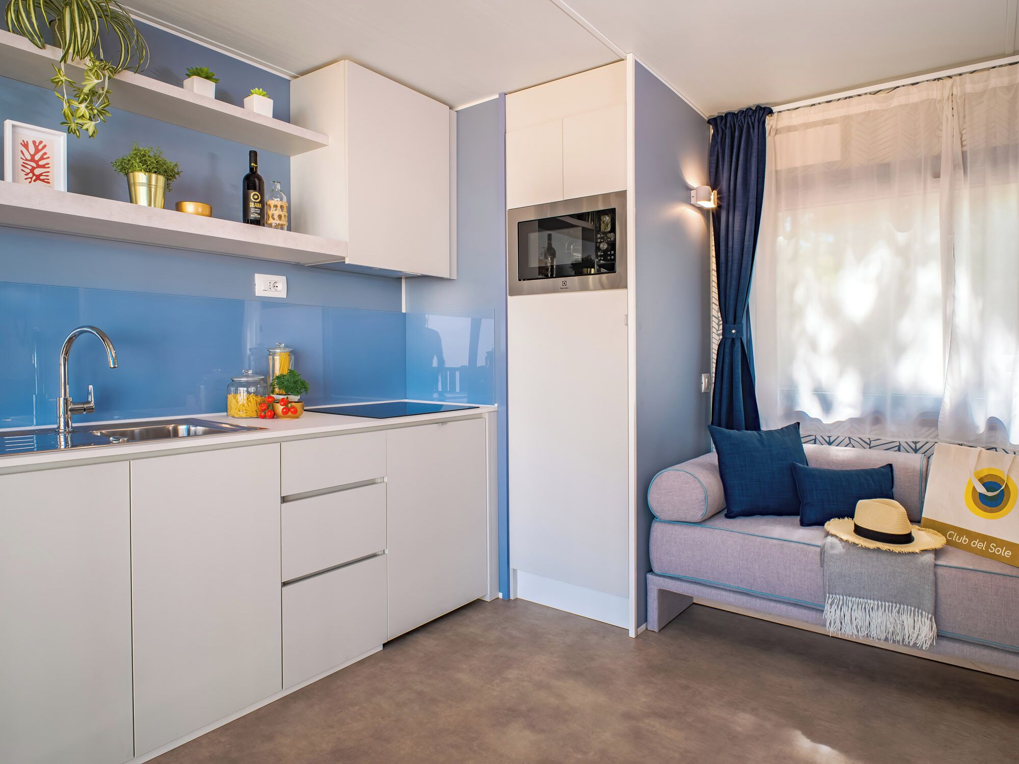 Een kleine keuken met een spoelbak, aanrecht en bergkasten.
