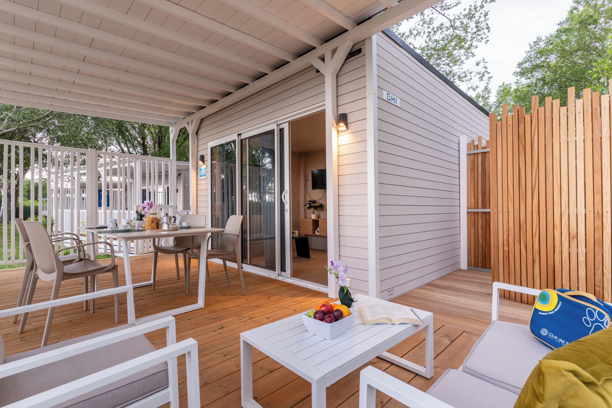 A covered outdoor area with a table, chairs, and a wooden deck.