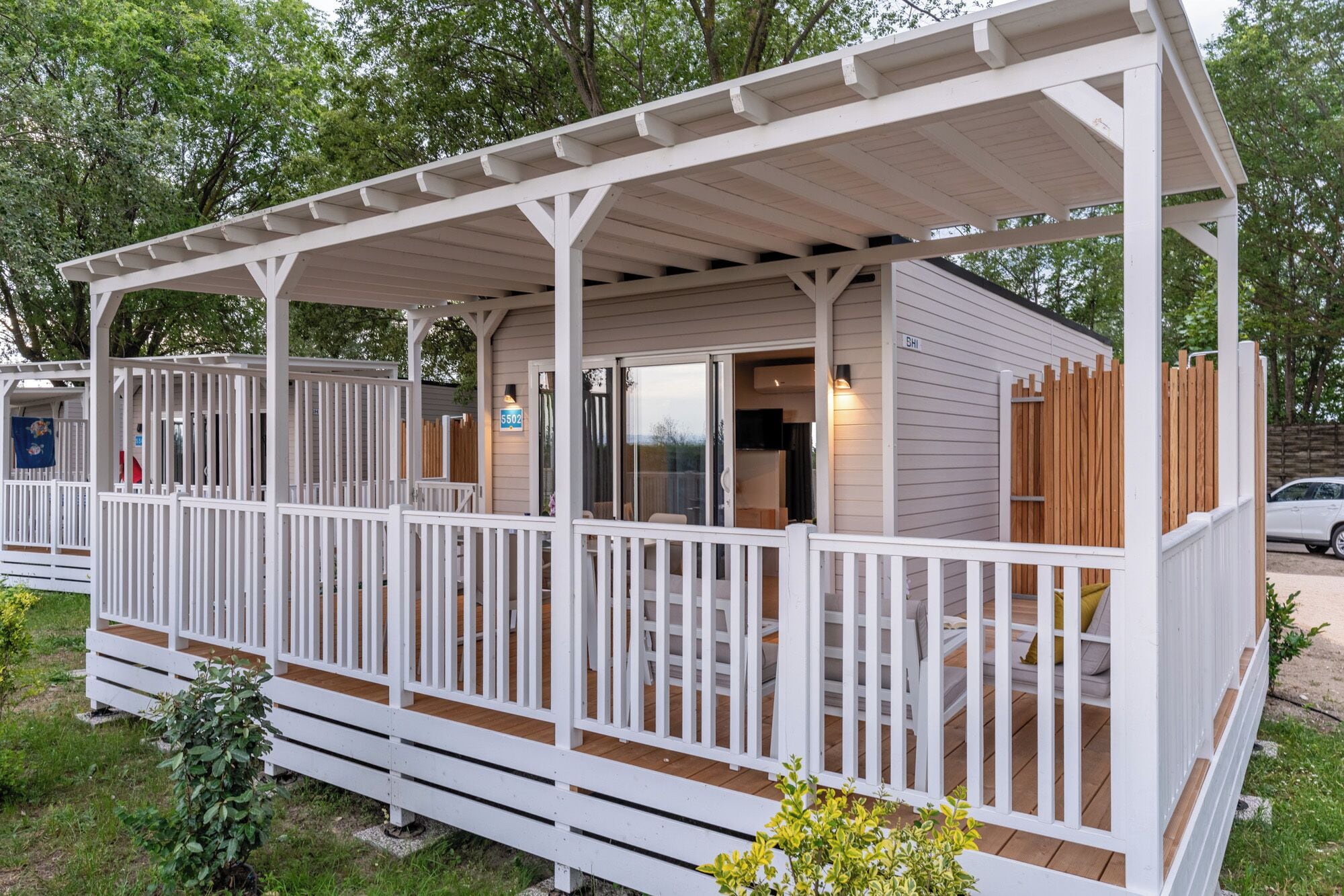 A white wooden structure with a covered porch and a fenced deck area.