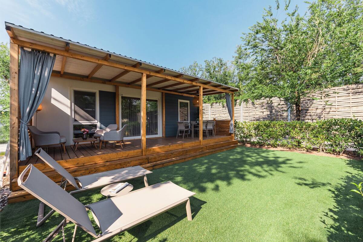 A covered outdoor area with a wooden deck, a dining table, and chairs.
