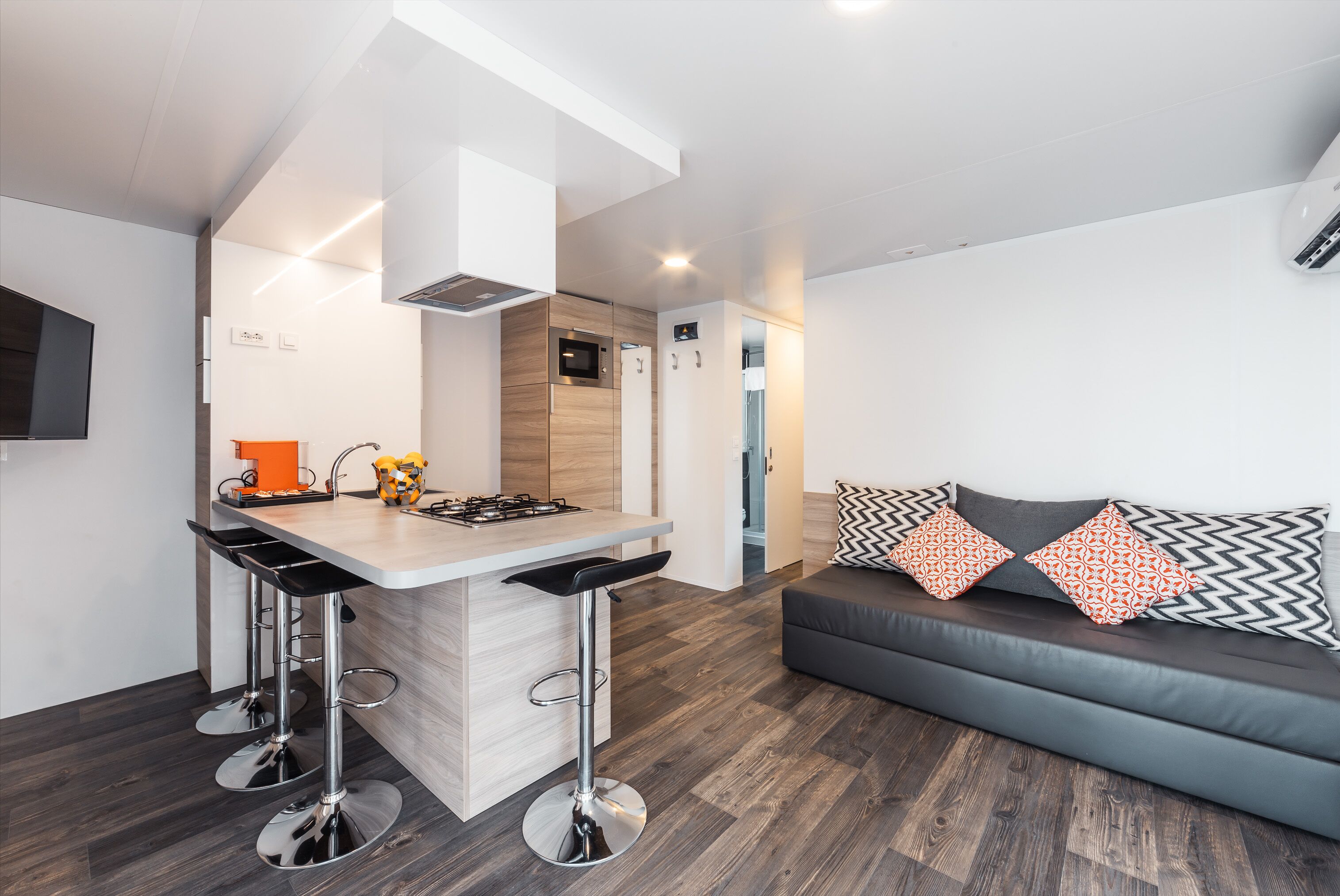 A modern kitchen with a central island, bar stools, and a built-in oven.