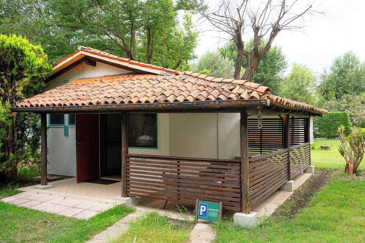 A bungalow with a tiled roof, a wooden porch, and a small garden area.