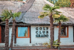 A building with a thatched roof and a sign reading 'GOLF CLUB GRADO'.